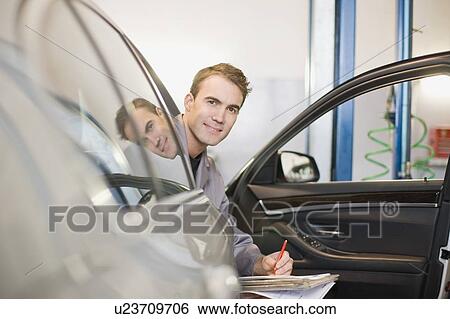 Stock Photograph - Mechanic in car smiling in garage. Fotosearch