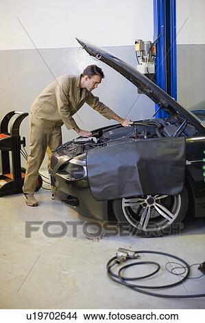 Picture - Mechanic working on car engine in garage. Fotosearch