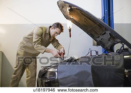 Mechanic working on car engine in garage View Large Photo Image Stock Photograph - Mechanic working on car engine in garage. Fotosearch