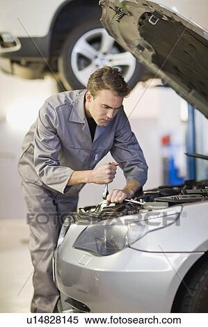 Stock Photography - Mechanic working on car engine in garage. Fotosearch