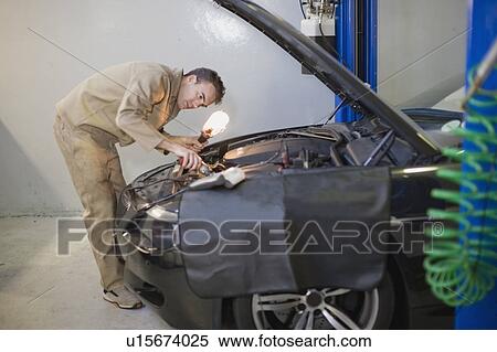 Mechanic working on car engine in garage View Large Photo Image Stock Photography - Mechanic working on car engine in garage. Fotosearch