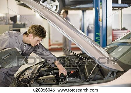 Stock Photography - Mechanic working on car engine in garage. Fotosearch