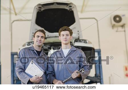 Stock Photo - Mechanics standing together in garage. Fotosearch