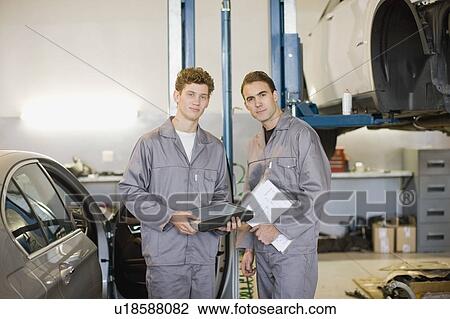 Stock Image - Mechanics working in garage. Fotosearch