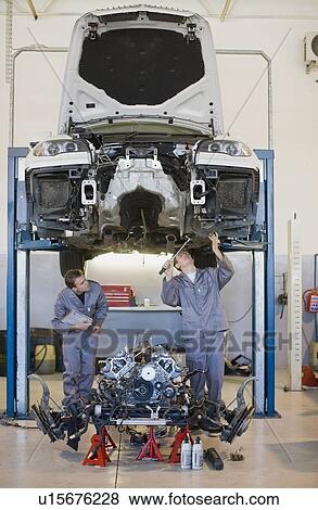 Stock Photo - Mechanics working on car in garage. Fotosearch