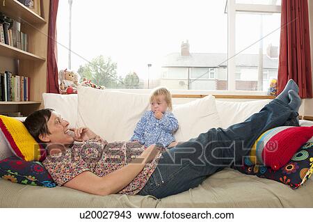 Stock Image - Mother and daughter relaxing on couch. Fotosearch