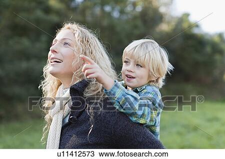 Mother carrying son piggyback outdoors View Large Photo Image Stock Image - Mother carrying son piggyback outdoors. Fotosearch