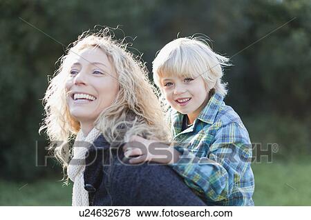 Stock Photo - Mother carrying son piggyback outdoors. Fotosearch