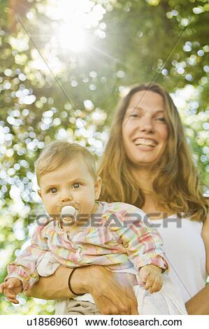 Stock Image - Mother holding baby with pacifier. Fotosearch