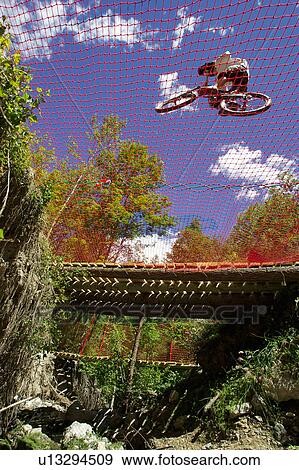 Mountain biker on netting over ditch View Large Photo Image Stock Photo - Mountain biker on netting over ditch. Fotosearch