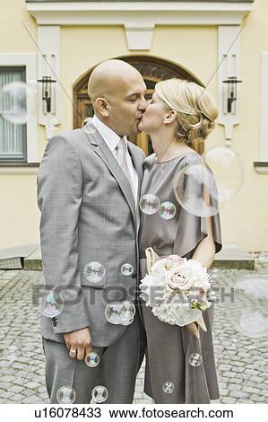 Stock Image - Newlywed couple kissing on city street. Fotosearch