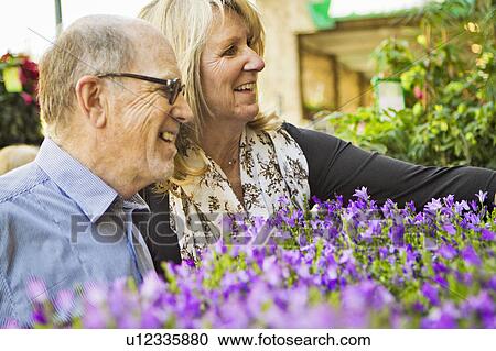 Stock Image - Older couple admiring flowers. Fotosearch