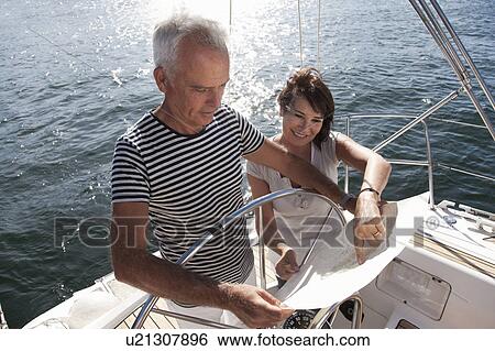 Stock Photograph - Older couple reading map on sailboat. Fotosearch