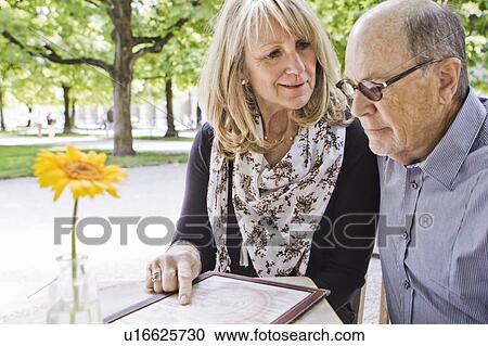 Stock Image - Older couple reading menu at cafe. Fotosearch