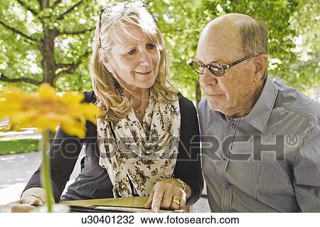 Stock Image - Older couple reading menu at cafe. Fotosearch