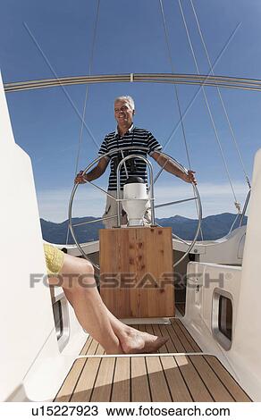 Stock Image - Older couple relaxing on sailboat. Fotosearch