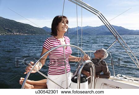 Stock Image - Older couple relaxing on sailboat. Fotosearch