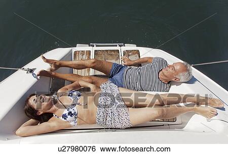 Stock Photograph - Older couple relaxing on sailboat. Fotosearch