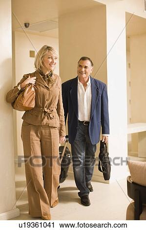 Older couple rolling luggage in walkway View Large Photo Image Stock Image - Older couple rolling luggage in walkway. Fotosearch
