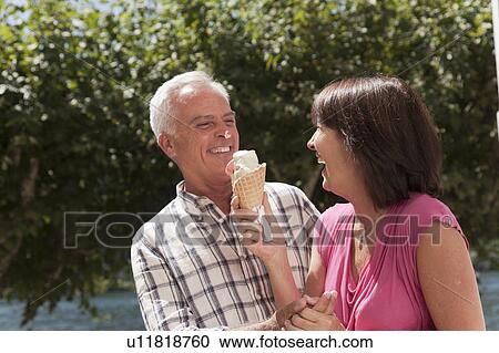 Stock Image - Older couple sharing ice cream cone. Fotosearch