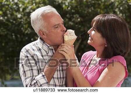Stock Image - Older couple sharing ice cream cone. Fotosearch