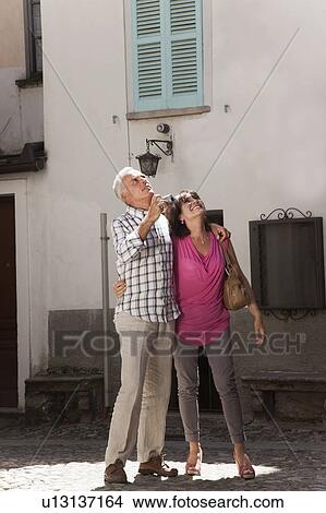 Picture - Older couple taking photos in village. Fotosearch