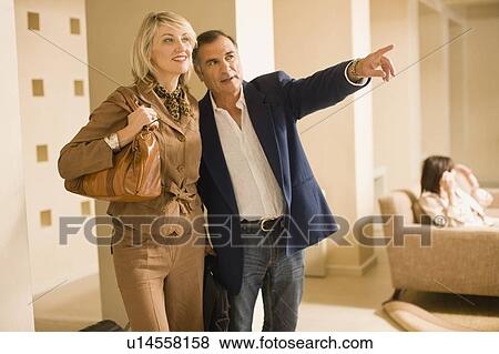 Stock Photo - Older couple walking in lobby area. Fotosearch