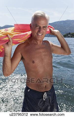 Stock Image - Older man drying off with towel on lake. Fotosearch