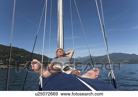 Stock Photo - Older man relaxing on sailboat. Fotosearch