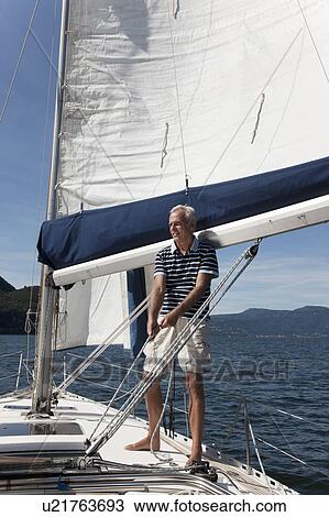 Stock Image - Older man sailing on lake. Fotosearch