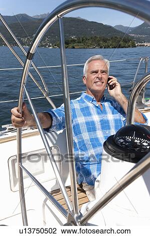 Older man talking on phone on sailboat View Large Photo Image Stock Image - Older man talking on phone on sailboat. Fotosearch
