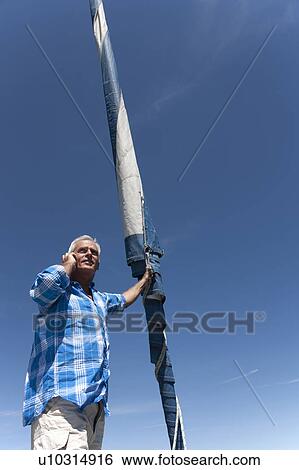 Older man talking on phone on sailboat View Large Photo Image Stock Photograph - Older man talking on phone on sailboat. Fotosearch