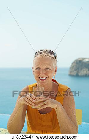 Stock Photo - Older woman having drink outdoors. Fotosearch