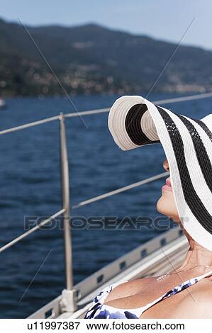 Stock Photo - Older woman wearing sunhat on sailboat. Fotosearch