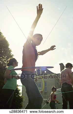 Stock Image - People hula hooping outdoors. Fotosearch