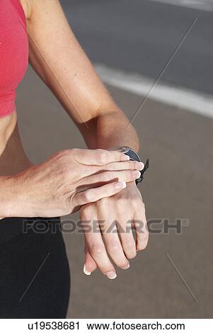 Stock Image - Runner checking her watch. Fotosearch