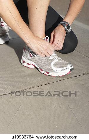 Picture - Runner tying her shoe. Fotosearch