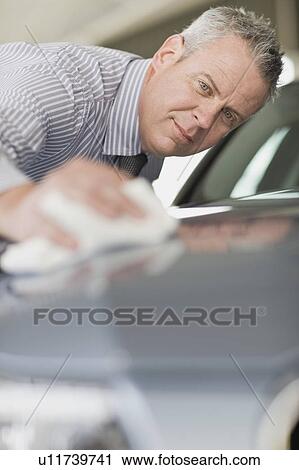 Salesman shining car in showroom View Large Photo Image Stock Image - Salesman shining car in showroom. Fotosearch