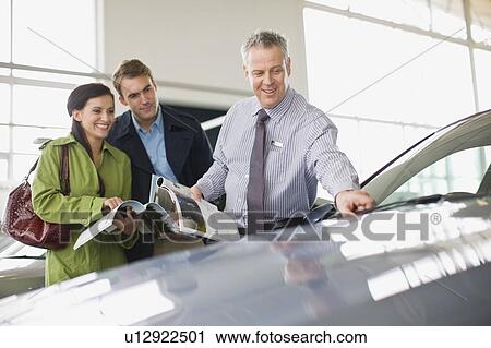 Salesman showing off car in showroom View Large Photo Image Stock Image - Salesman showing off car in showroom. Fotosearch