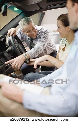 Salesman showing off car in showroom View Large Photo Image Stock Image - Salesman showing off car in showroom. Fotosearch