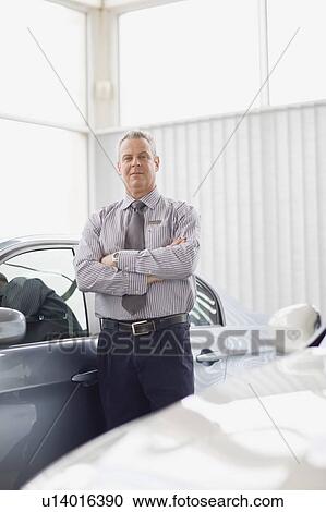Salesman standing by car in showroom View Large Photo Image Stock Image - Salesman standing by car in showroom. Fotosearch