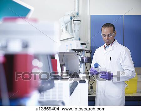 Scientist putting liquid in beaker View Large Photo Image Picture - Scientist putting liquid in beaker. Fotosearch