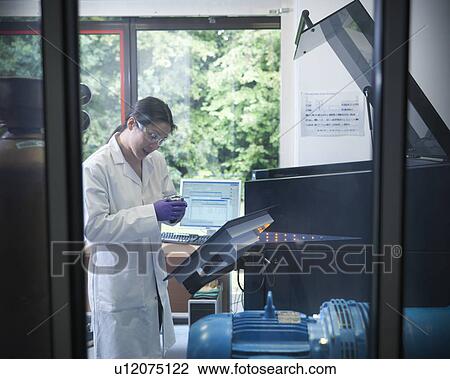 Stock Image - Scientist working on equipment in lab. Fotosearch