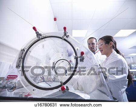 Stock Image - Scientists working on equipment in lab. Fotosearch