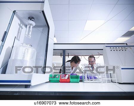 Stock Image - Scientists working on equipment in lab. Fotosearch
