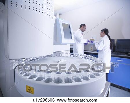 Stock Image - Scientists working on equipment in lab. Fotosearch