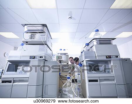 Stock Photo - Scientists working on equipment in lab. Fotosearch