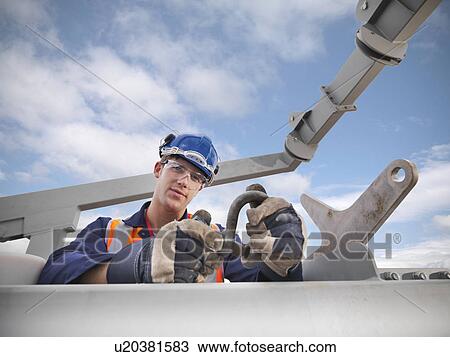 Stock Image - Shipbuilder working on lifeboat. Fotosearch