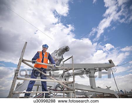 Stock Photo - Shipbuilder working on lifeboat. Fotosearch