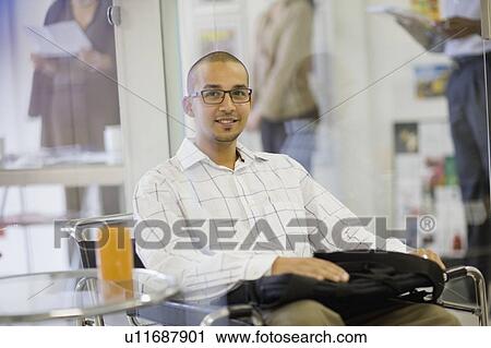 Stock Image - Smiling businessman sitting in office. Fotosearch